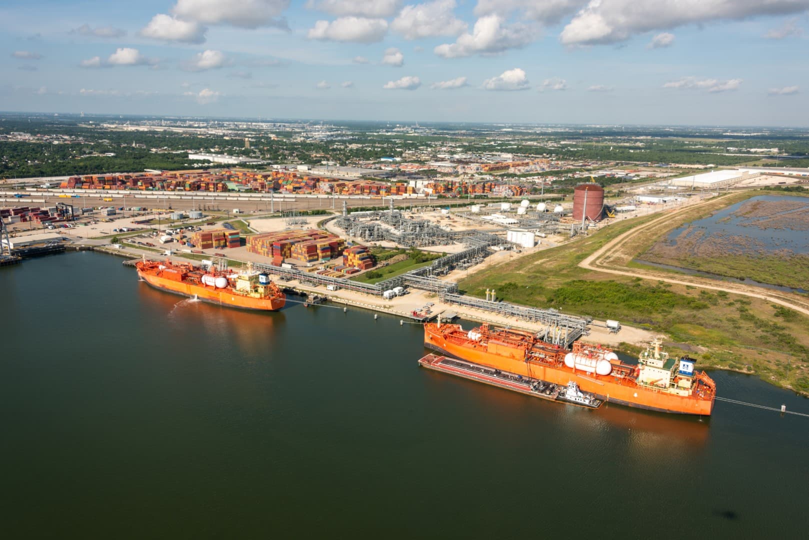 A modern gas ship navigating open seas, with large cylindrical tanks on deck used for transporting liquefied natural gas (LNG). The vessel’s sleek, robust design is evident against a backdrop of clear skies and calm waters, conveying a sense of safety and precision.
